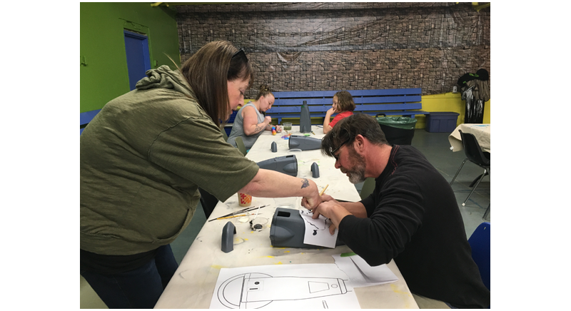 four participants working on painting parking meter cover